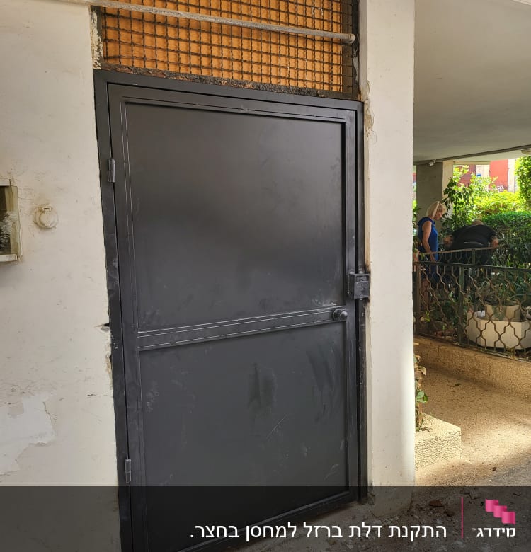 דלת מתכת שחורה עם מסגרת רשת מעליה